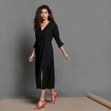 Left View of a Model wearing Black Handspun Cotton Surplice Neck Pleated Midi Dress