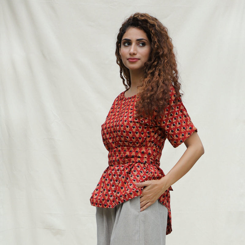 Left View of a Model wearing Brick Red Floral Block Printed Cotton Peplum Top