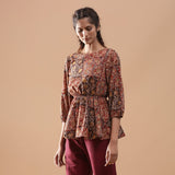 Left View of a Model wearing Muddy Red Kalamkari Block Print Cotton Peplum Top