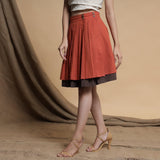Left View of a Model wearing Orange and Brown Reversible Pleated Flared Skirt