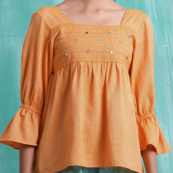 Front Detail of a Model wearing Orange Handspun Yoked Mirror Top