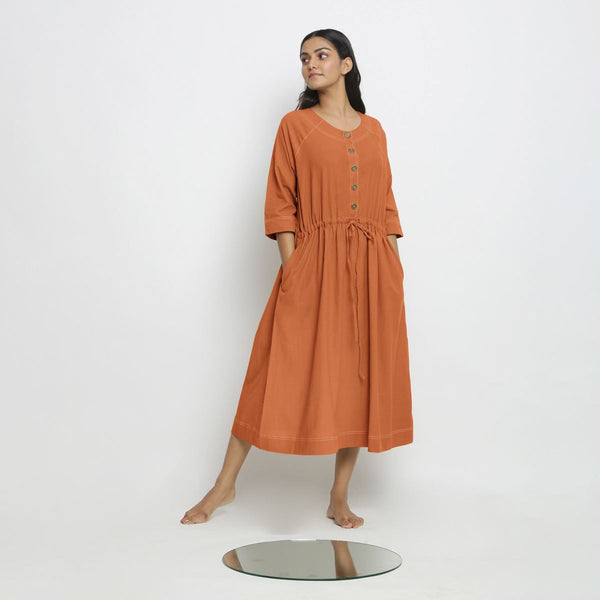 Right View of a Model wearing Vegetable-Dyed Orange 100% Cotton Button-Down Dress