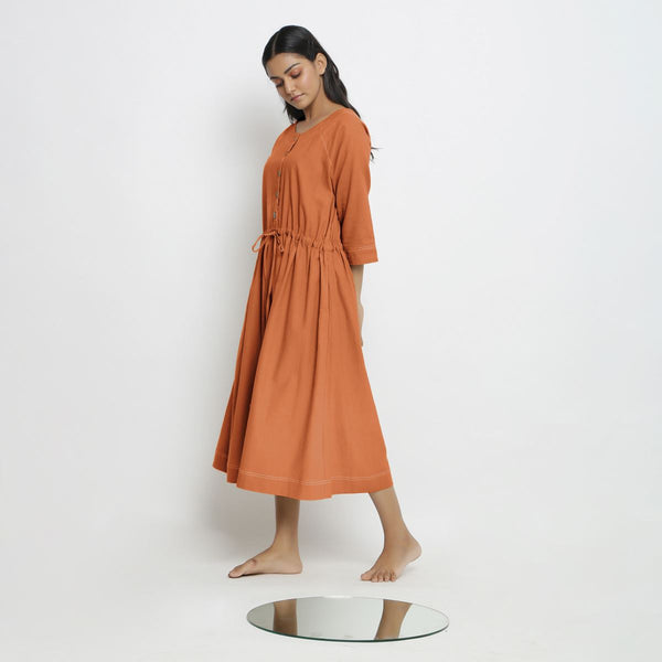 Left View of a Model wearing Vegetable-Dyed Orange 100% Cotton Button-Down Dress