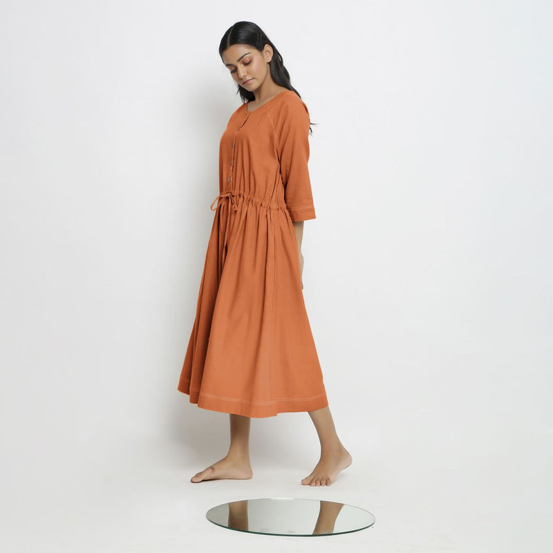 Left View of a Model wearing Vegetable-Dyed Orange 100% Cotton Button-Down Dress