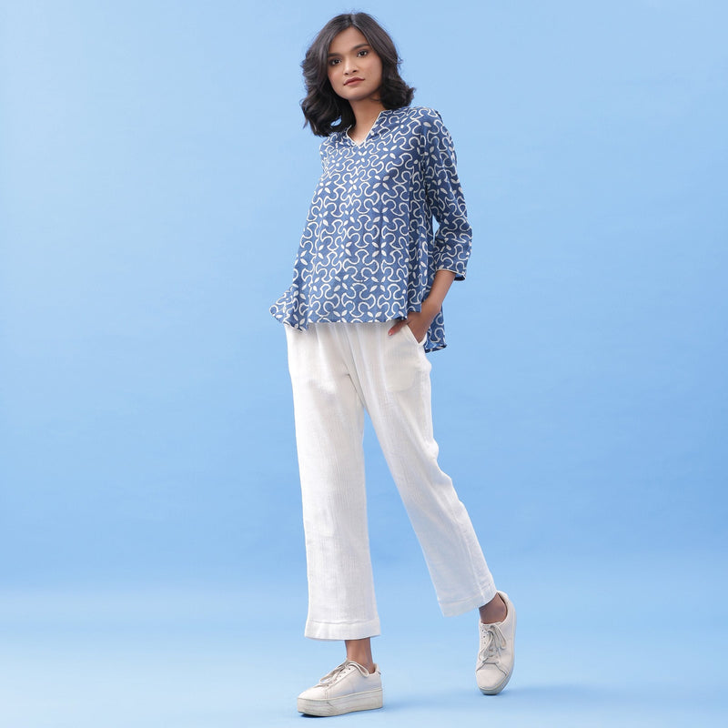 Left View of a Model wearing Indigo Flared Top and Off-White Tapered Pant Set