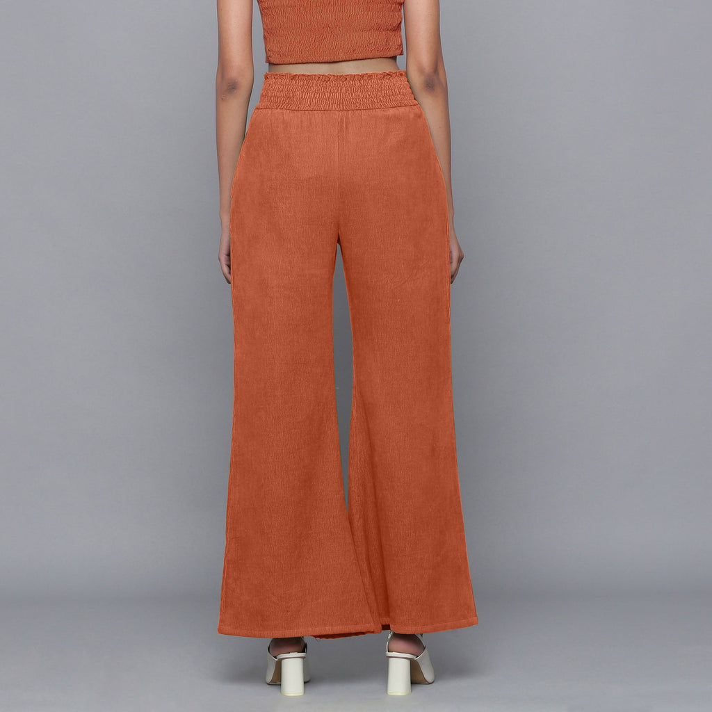 Back View of a Model wearing Sunset Rust Corduroy Striped Bootcut Pant