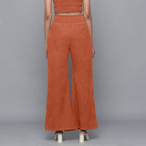 Back View of a Model wearing Sunset Rust Corduroy Striped Bootcut Pant